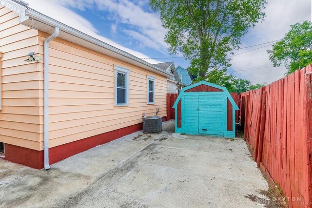 view of side of property with central AC unit, a patio area, and a storage shed