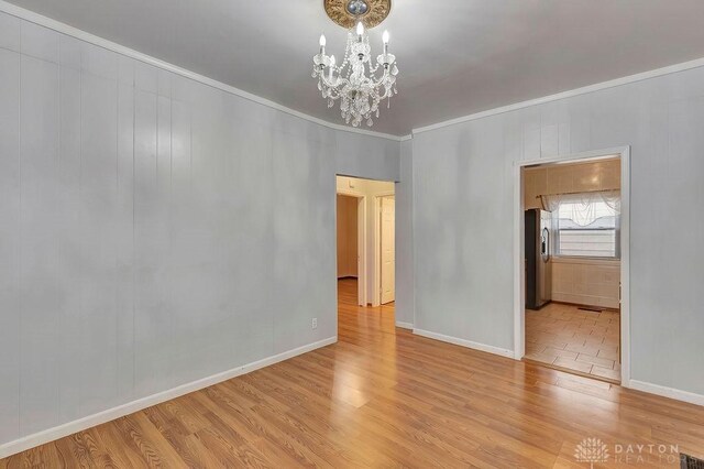 spare room with a chandelier, crown molding, and light tile patterned floors