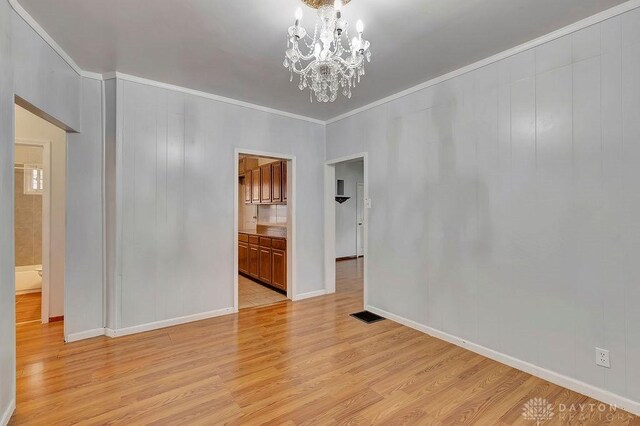 unfurnished room with light hardwood / wood-style floors, a chandelier, and ornamental molding