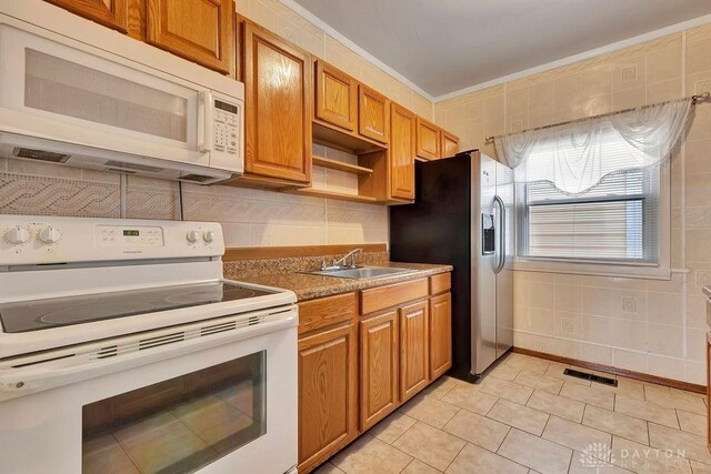 kitchen with white appliances, sink, tile walls, light tile patterned floors, and crown molding