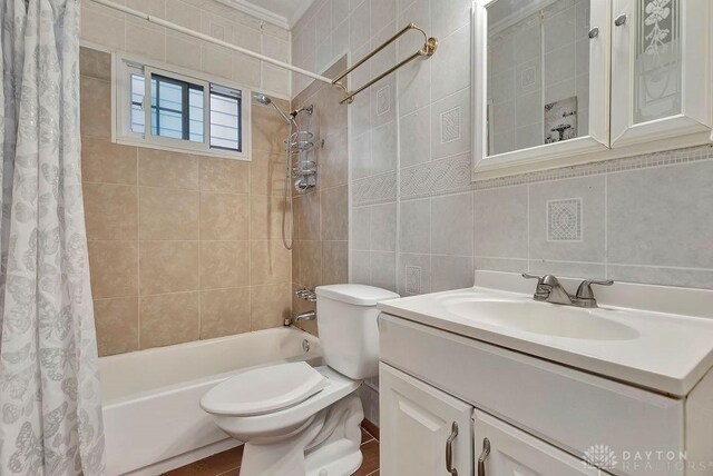 full bathroom with tasteful backsplash, shower / bath combination with curtain, tile walls, toilet, and vanity