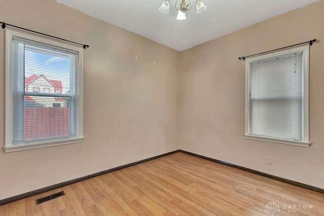 spare room featuring a notable chandelier and light hardwood / wood-style flooring