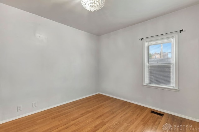 empty room featuring light hardwood / wood-style floors and a notable chandelier