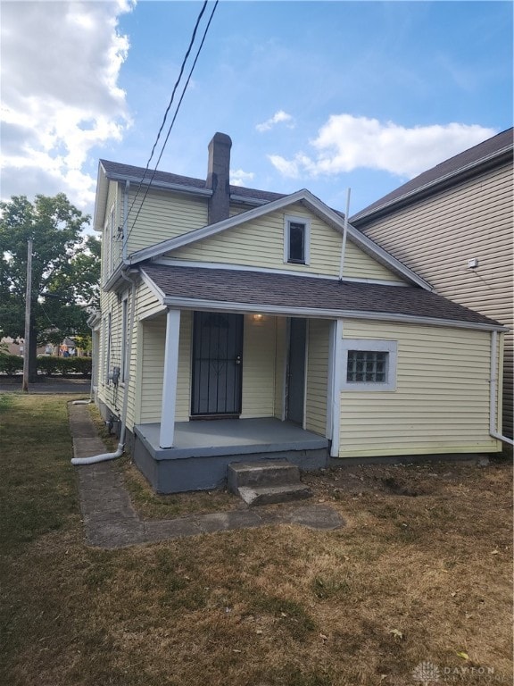 rear view of property featuring a lawn and a porch