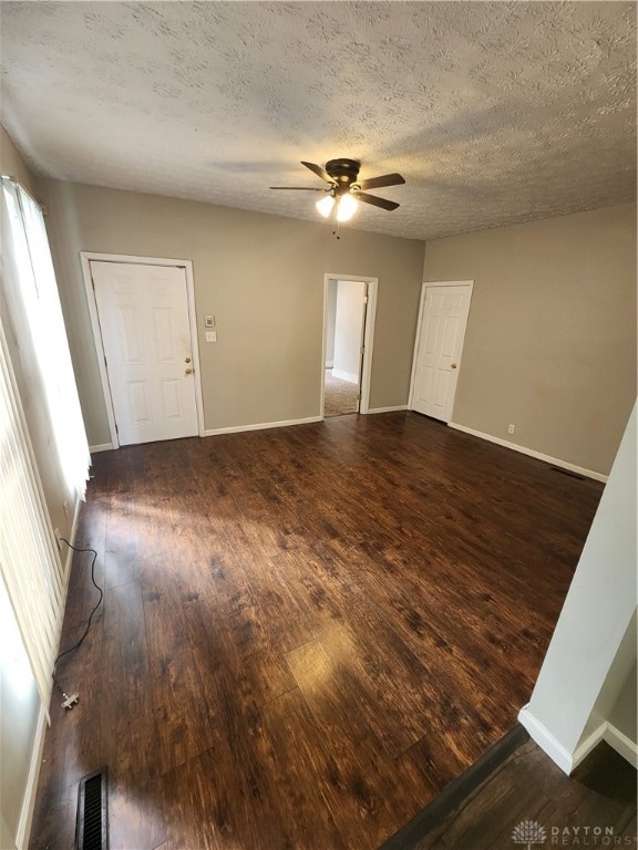 spare room featuring dark wood-type flooring, a textured ceiling, and ceiling fan