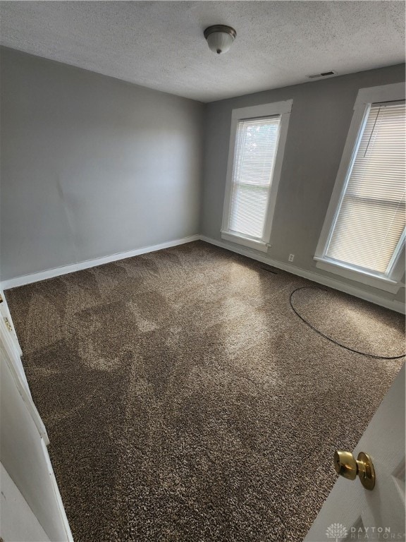 empty room with a textured ceiling and carpet