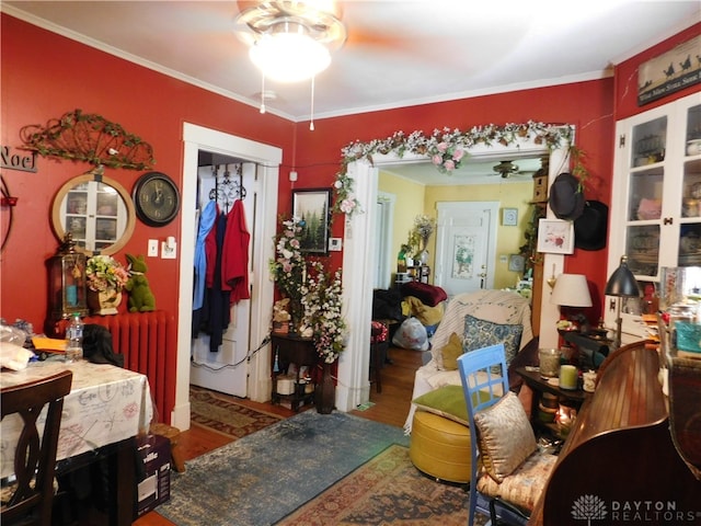 interior space featuring dark wood-type flooring, radiator, crown molding, and ceiling fan