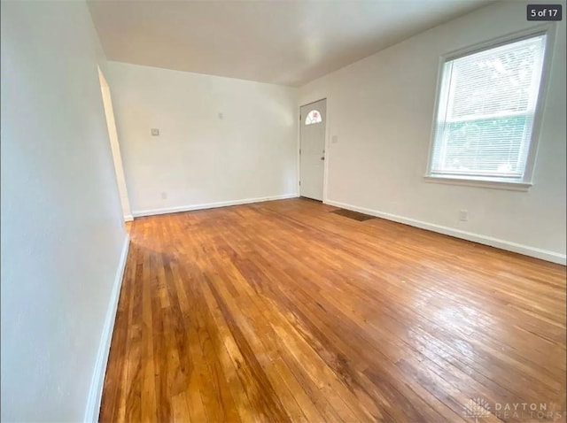 spare room featuring a healthy amount of sunlight and light hardwood / wood-style floors