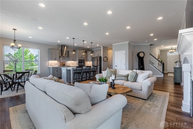 living room featuring crown molding, dark wood-type flooring, and an inviting chandelier