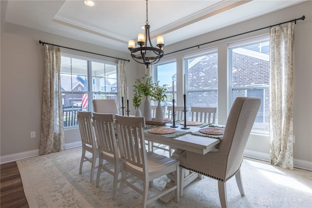 dining area featuring a tray ceiling, a healthy amount of sunlight, and a notable chandelier