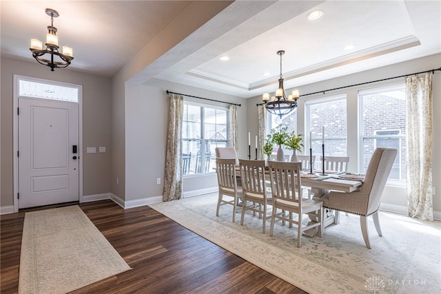 dining area with dark hardwood / wood-style flooring, a raised ceiling, crown molding, and a chandelier