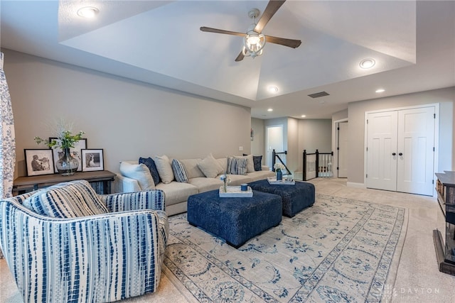 carpeted living room with a tray ceiling and ceiling fan