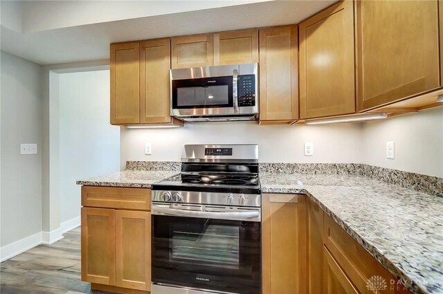 kitchen featuring light stone counters, appliances with stainless steel finishes, and light hardwood / wood-style floors