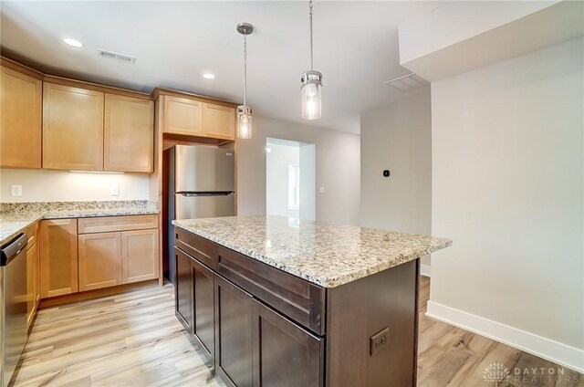 kitchen with dishwasher, light stone countertops, a center island, and light wood-type flooring