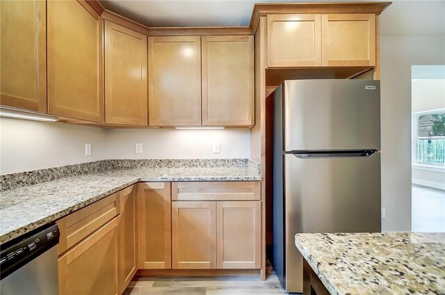 kitchen with light stone counters, appliances with stainless steel finishes, and light hardwood / wood-style floors