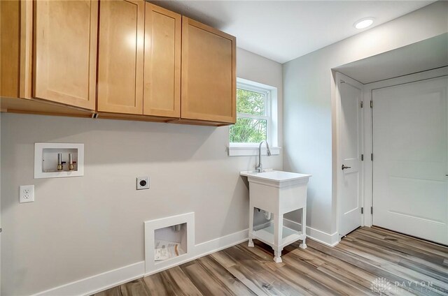 clothes washing area with electric dryer hookup, washer hookup, cabinets, and light wood-type flooring