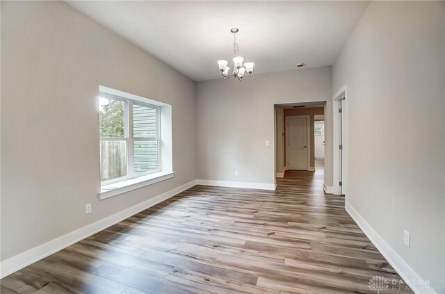 unfurnished dining area with a notable chandelier and light wood-type flooring