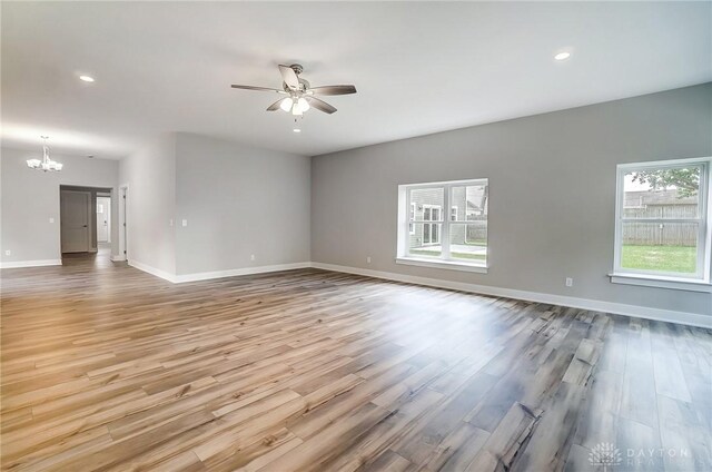 unfurnished room with ceiling fan with notable chandelier and hardwood / wood-style flooring