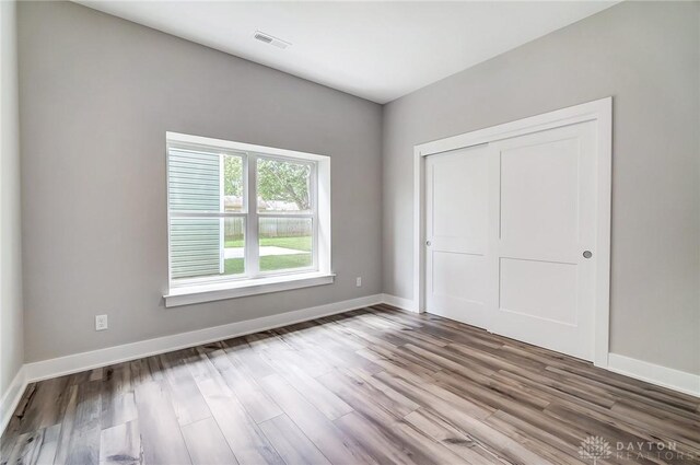 unfurnished bedroom featuring wood-type flooring and a closet