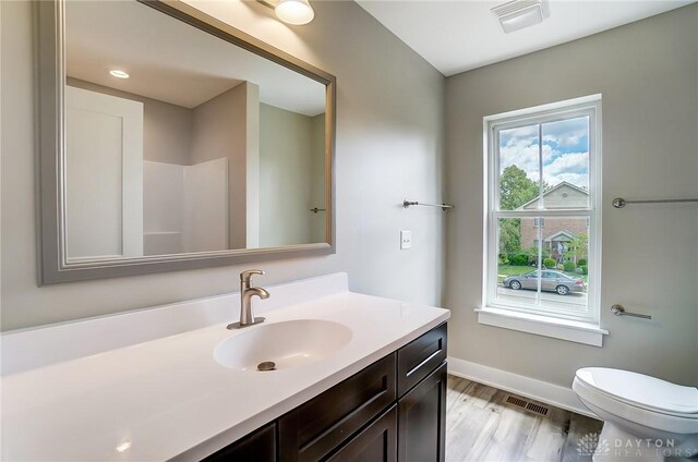 bathroom featuring hardwood / wood-style flooring, vanity, walk in shower, and toilet