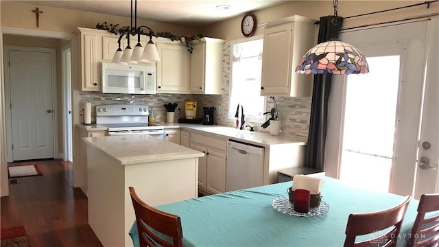 kitchen with sink, white appliances, a kitchen island, decorative light fixtures, and decorative backsplash