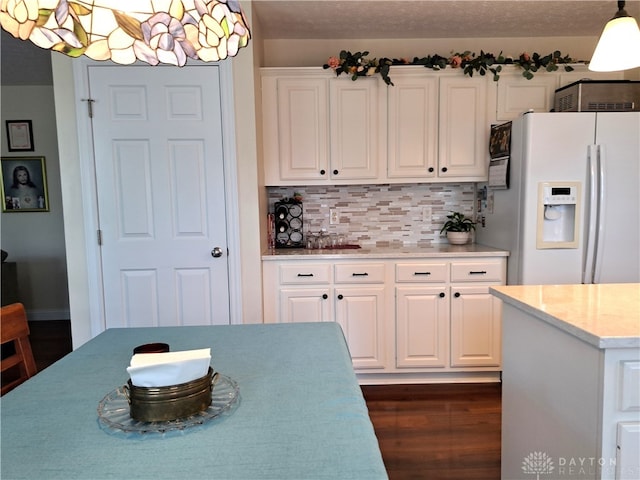 kitchen featuring hanging light fixtures, tasteful backsplash, dark wood-type flooring, white cabinetry, and white refrigerator with ice dispenser