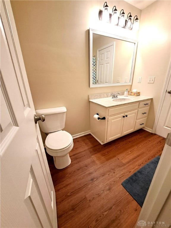 bathroom with wood-type flooring, vanity, and toilet