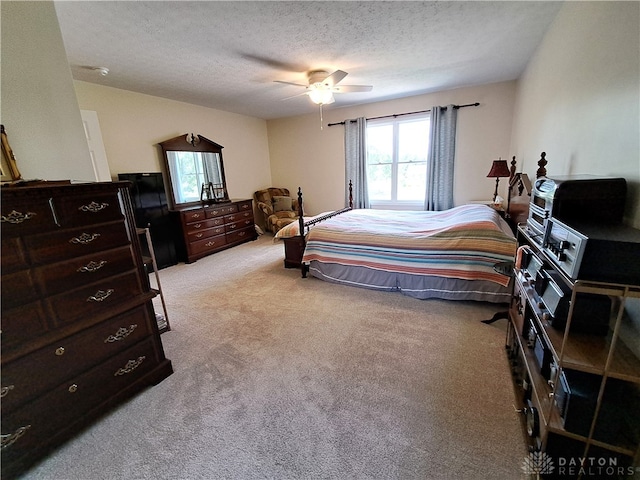 bedroom with ceiling fan, a textured ceiling, and light carpet