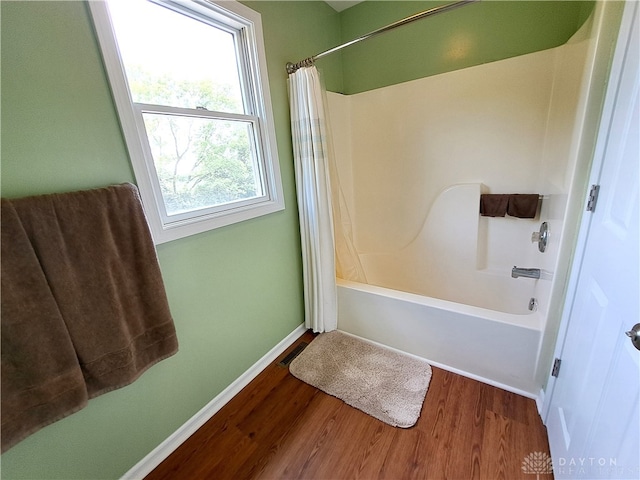 bathroom with hardwood / wood-style floors, shower / bath combo, and a healthy amount of sunlight