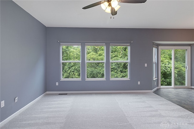 carpeted spare room with ceiling fan and plenty of natural light