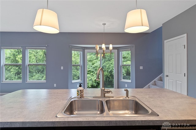 kitchen featuring hanging light fixtures, sink, an inviting chandelier, and a center island with sink