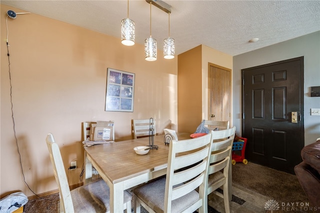 dining area featuring a textured ceiling and dark carpet