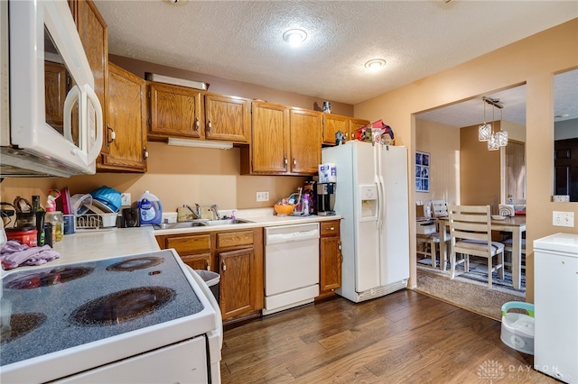 kitchen featuring decorative light fixtures, white appliances, dark wood-type flooring, a textured ceiling, and sink