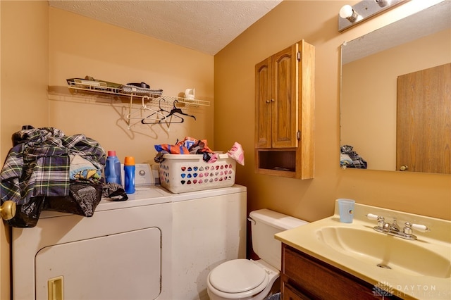 bathroom featuring a textured ceiling, washer and clothes dryer, vanity, and toilet