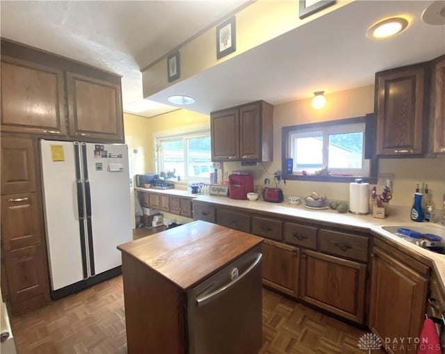 kitchen with dark parquet floors, stainless steel dishwasher, a healthy amount of sunlight, and white refrigerator