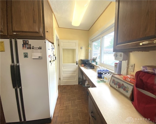 kitchen with white fridge, dark brown cabinets, and dark parquet floors