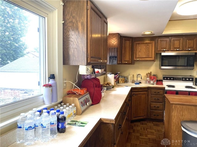 kitchen with white electric stove, a healthy amount of sunlight, sink, and dark parquet floors