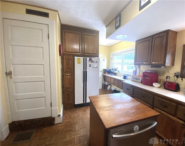 kitchen featuring white refrigerator, dark parquet flooring, and dark brown cabinetry