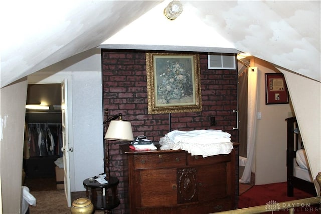 bedroom with brick wall, lofted ceiling, a spacious closet, and a closet