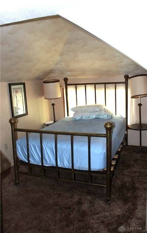 bedroom with vaulted ceiling and dark colored carpet