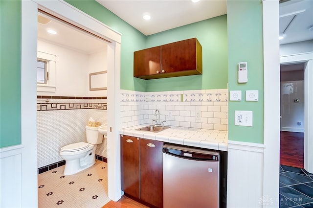 bathroom featuring tile patterned flooring, toilet, tile walls, and sink