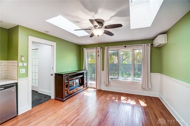 unfurnished living room featuring a skylight, light hardwood / wood-style flooring, and a healthy amount of sunlight