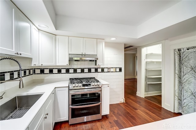 kitchen with white cabinets, sink, decorative backsplash, dark hardwood / wood-style flooring, and stainless steel range with gas stovetop