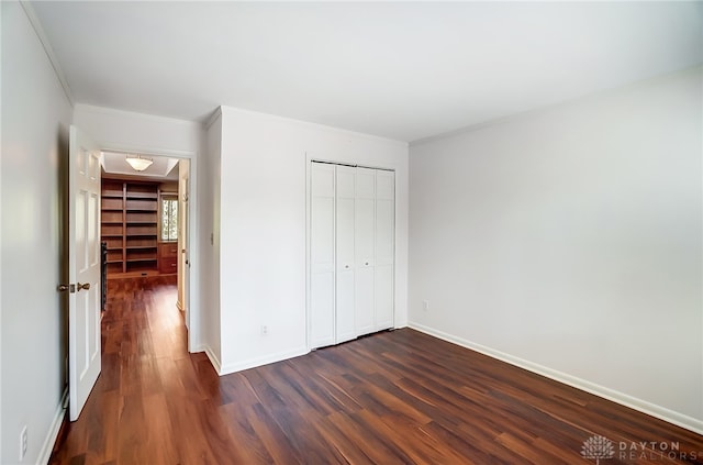 unfurnished bedroom with crown molding, a closet, and dark hardwood / wood-style floors