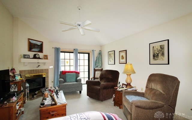 living room featuring carpet floors, lofted ceiling, ceiling fan, and a tiled fireplace