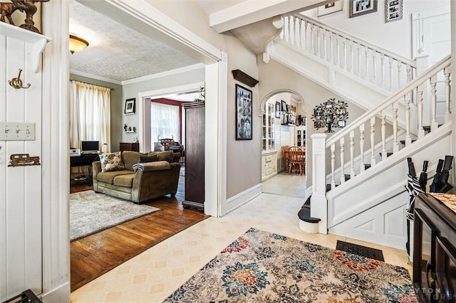 foyer with crown molding, a textured ceiling, and light wood-type flooring