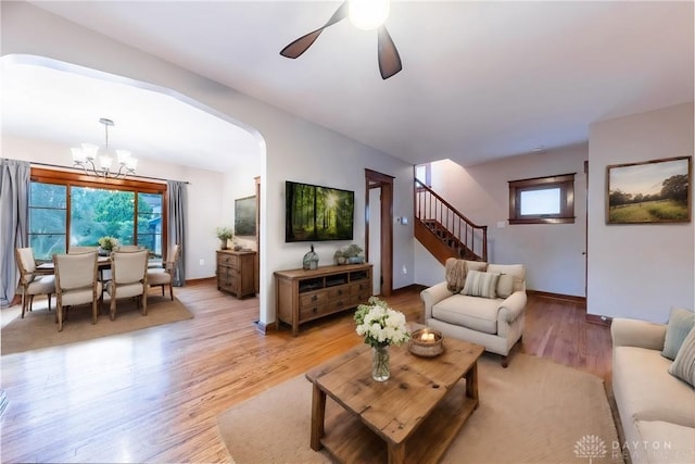 living room featuring ceiling fan with notable chandelier, light wood-type flooring, and a healthy amount of sunlight