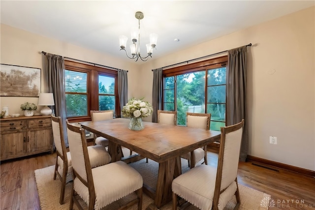 dining space with hardwood / wood-style flooring and a chandelier