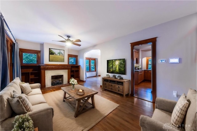 living room with ceiling fan, dark hardwood / wood-style flooring, and a fireplace