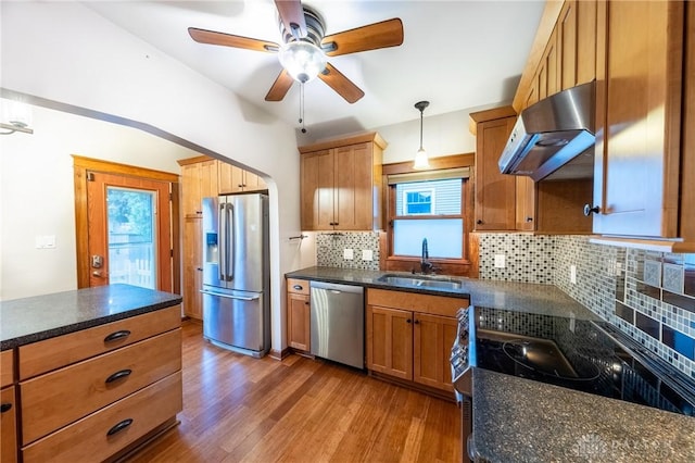 kitchen with sink, decorative light fixtures, hardwood / wood-style floors, extractor fan, and appliances with stainless steel finishes